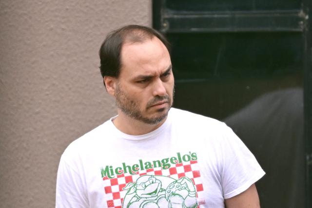 Rio de Janeiro's Councillor, Carlos Bolsonaro, son of former Brazilian President Jair Bolsonaro, leaves the Federal Police headquarters where his father is being held, in Brasilia, on November 25, 2025. Brazil's Supreme Court on November 24 voted to uphold the imprisonment of former president Jair Bolsonaro, who was detained over the weekend for tampering with his ankle monitor using a soldering iron. (Photo by Evaristo SA / AFP)