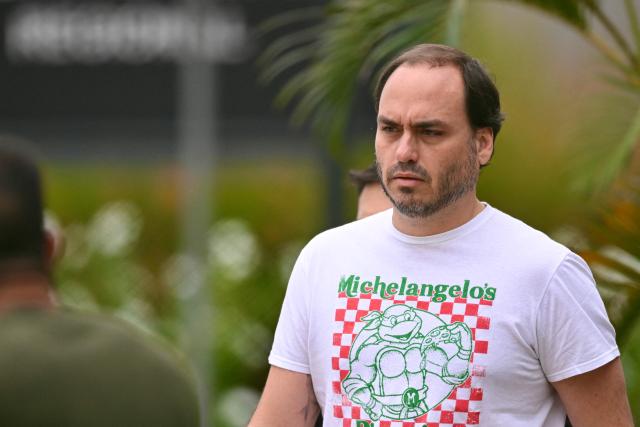 Rio de Janeiro's Councillor, Carlos Bolsonaro, son of former Brazilian President Jair Bolsonaro, leaves the Federal Police headquarters where his father is being held, in Brasilia, on November 25, 2025. Brazil's Supreme Court on November 24 voted to uphold the imprisonment of former president Jair Bolsonaro, who was detained over the weekend for tampering with his ankle monitor using a soldering iron. (Photo by Evaristo SA / AFP)