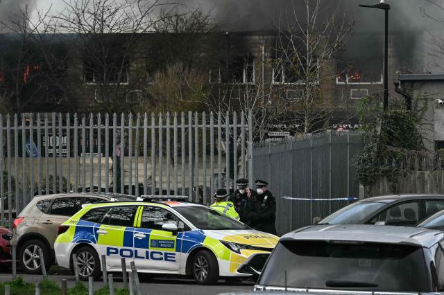 Police wear facemasks to protect from the thick smoke as it rises into the air while over 100 members of the fire services battle a large fire which broke out at a warehouse in the Southall area in western London on November 25, 2025. (Photo by JUSTIN TALLIS / AFP)