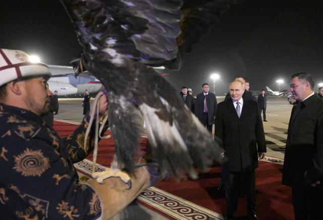 In this pool photograph distributed by the Russian state agency Sputnik, Russia's President Vladimir Putin and Kyrgyz President Sadyr Japarov attend a welcoming ceremony upon the Russian leader's arrival at Bishkek's Manas airport on November 25, 2025, the first day of his three-day state visit to Kyrgyzstan. (Photo by Alexey NIKOLSKY / POOL / AFP)