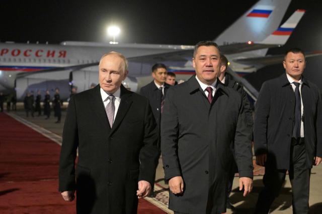 In this pool photograph distributed by the Russian state agency Sputnik, Russia's President Vladimir Putin and Kyrgyz President Sadyr Japarov attend a welcoming ceremony upon the Russian leader's arrival at Bishkek's Manas airport on November 25, 2025, the first day of his three-day state visit to Kyrgyzstan. (Photo by Alexey NIKOLSKY / POOL / AFP)