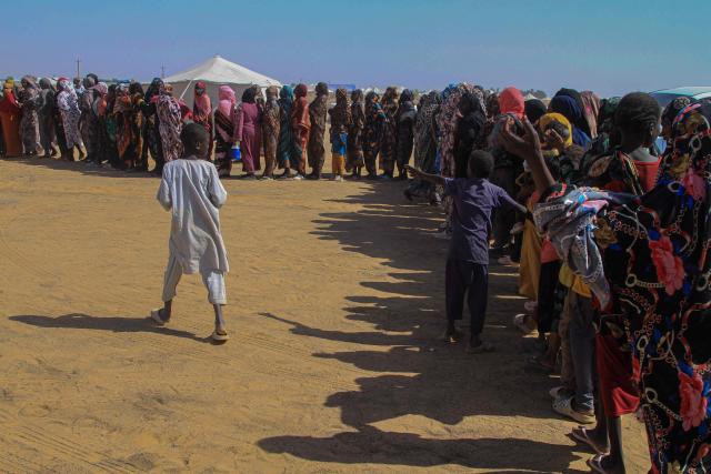 Sudanese women who fled El-Fasher line up to receive humanitarian aid at the Al-Afad camp for displaced people in the town of Al-Dabba, northern Sudan, on November 25, 2025. Sudan's army said on November 25 it had repelled a Rapid Support Forces attack on a strategic city in southern Kordofan, a day after the RSF declared a unilateral three-month ceasefire. In a statement, the military, which has been at war with the RSF since April 2023, said its troops had "pushed back an assault" on an infantry base in the town of Babanusa. (Photo by Ebrahim HAMID / AFP)