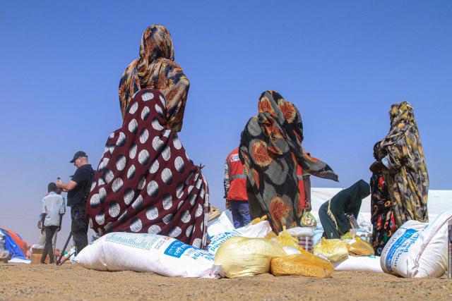 Sudanese women who fled El-Fasher receive humanitarian aid at the Al-Afad camp for displaced people in the town of Al-Dabba, northern Sudan, on November 25, 2025. Sudan's army said on November 25 it had repelled a Rapid Support Forces attack on a strategic city in southern Kordofan, a day after the RSF declared a unilateral three-month ceasefire. In a statement, the military, which has been at war with the RSF since April 2023, said its troops had "pushed back an assault" on an infantry base in the town of Babanusa. (Photo by Ebrahim HAMID / AFP)