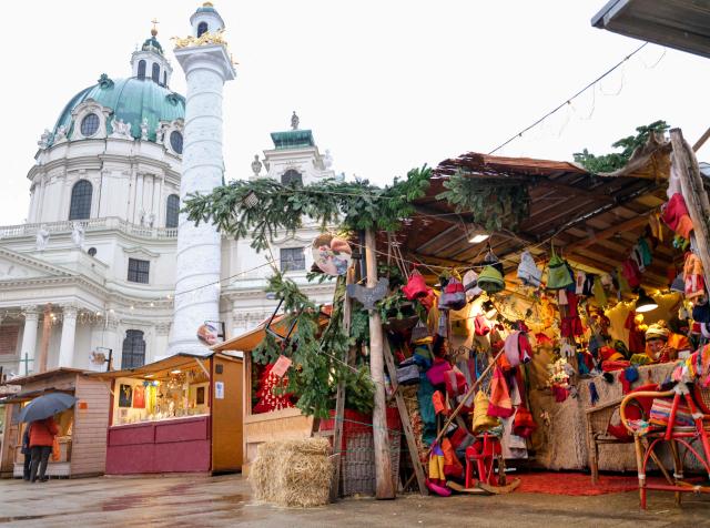 A vendor waits for customers at an empty Christmas market on a rainy day at Charles’ square (Karlsplatz) in Vienna, Austria on November 25, 2025. A recent cold wave brought rain, snow and sub zero temperatures to the Austrian capital. (Photo by Joe Klamar / AFP)