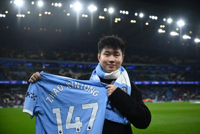 Chinese snooker player Zhao Xintong poses with a 147 shirt ahead od the UEFA Champions League league-stage football match between Manchester City and Bayer Leverkusen at the Etihad Stadium in Manchester, north west England, on November 25, 2025. (Photo by Oli SCARFF / AFP)