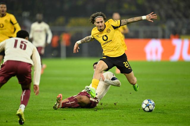 Dortmund's Portuguese forward #21 Fabio Silva (R) and Villarreal's Spanish midfielder #14 Santi Comesana (bottom) vie for the ball during the UEFA Champions League league phase day 5 football match between Borussia Dortmund and Villareal CF in Dortmund, on November 25, 2025. (Photo by INA FASSBENDER / AFP)