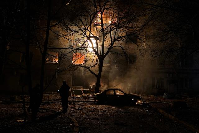 TOPSHOT - Local residents look on as a residential building burns following an air attack in Zaporizhzhia on November 25, 2025, amid the Russian invasion of Ukraine. (Photo by Darya NAZAROVA / AFP)
