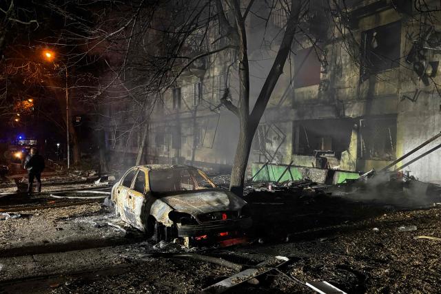 A man stands next to a burnt out car in the courtyard of a damaged residential building following an air attack in Zaporizhzhia on November 25, 2025, amid the Russian invasion of Ukraine. (Photo by Darya NAZAROVA / AFP)