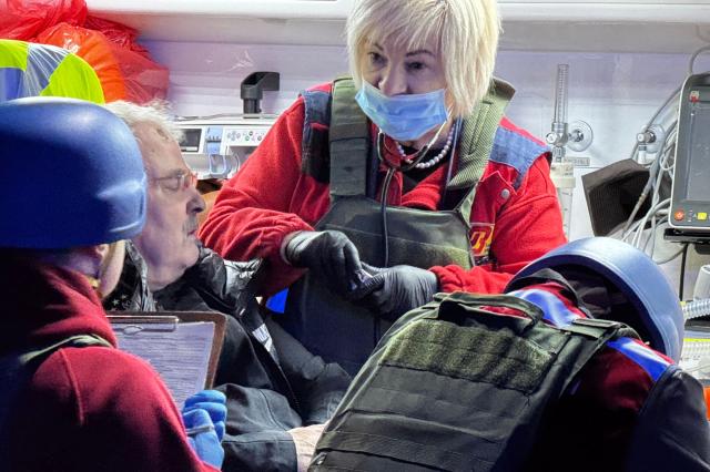 Emergency service personel provide assistance to a local resident following an air attack in Zaporizhzhia on November 25, 2025, amid the Russian invasion of Ukraine. (Photo by Darya NAZAROVA / AFP)