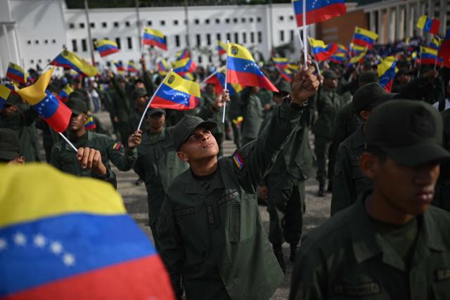 Members of the Bolivarian National Armed Force (FANB) wave the Venezuelan flag during a military ceremony at Fuerte Tiuna, in Caracas on November 25, 2025. (Photo by Federico PARRA / AFP)
