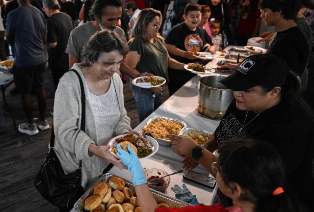 Volunteers serve food during the "Turkey and Blessing" dinner at Lindale Church in Houston on November 25, 2025, to celebrate the upcoming Thanksgiving holiday. (Photo by RONALDO SCHEMIDT / AFP)