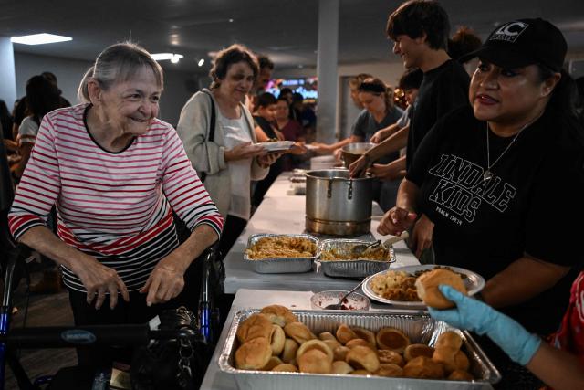 Volunteers serve food during the "Turkey and Blessing" dinner at Lindale Church in Houston on November 25, 2025, to celebrate the upcoming Thanksgiving holiday. (Photo by RONALDO SCHEMIDT / AFP)