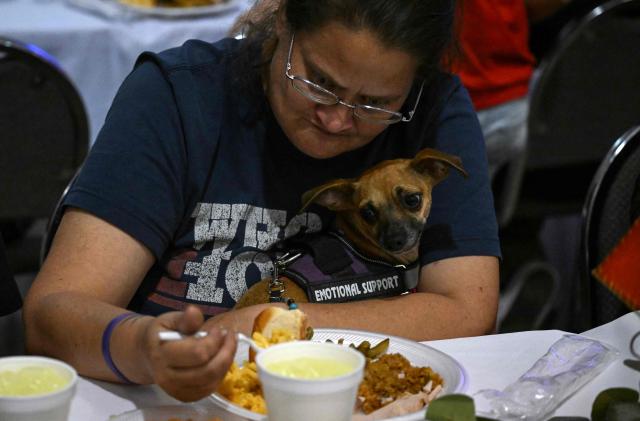 A woman eats with her emotional support dog during the "Turkey and Blessing" dinner at Lindale Church in Houston on November 25, 2025, to celebrate the upcoming Thanksgiving holiday. (Photo by RONALDO SCHEMIDT / AFP)