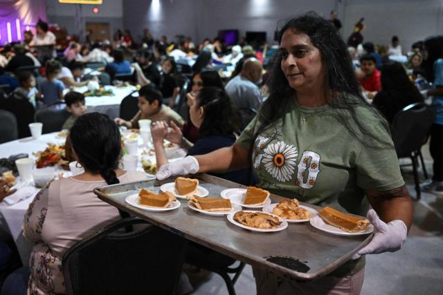 A volunteer serves food during the "Turkey and Blessing" dinner at Lindale Church in Houston on November 25, 2025, to celebrate the upcoming Thanksgiving holiday. (Photo by RONALDO SCHEMIDT / AFP)