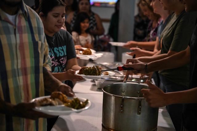 Volunteers serve food during the "Turkey and Blessing" dinner at Lindale Church in Houston on November 25, 2025, to celebrate the upcoming Thanksgiving holiday. (Photo by RONALDO SCHEMIDT / AFP)
