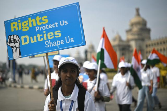 Students hold India's national flags as they participate in a rally to mark Constitution Day, at Vidhana Soudha in Bengaluru on November 26, 2025. (Photo by Idrees MOHAMMED / AFP)
