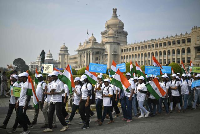 Students hold India's national flags as they participate in a rally to mark Constitution Day, at Vidhana Soudha in Bengaluru on November 26, 2025. (Photo by Idrees MOHAMMED / AFP)