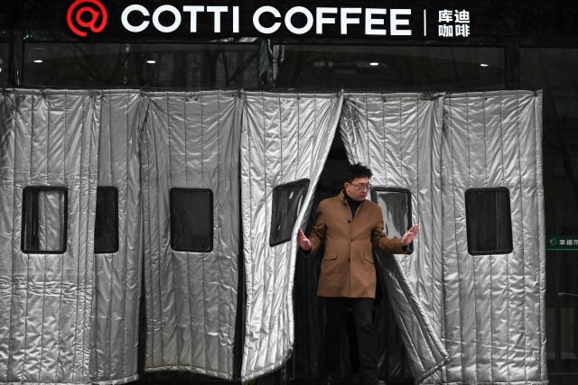 A man leaves a shopping mall under the Cotti Coffee sign in Beijing on November 26, 2026. (Photo by Pedro PARDO / AFP)