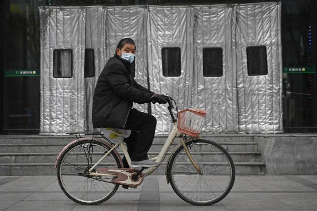 A man rides his bicycle past the entrance of a shopping mall in Beijing on November 26, 2026. (Photo by Pedro PARDO / AFP)