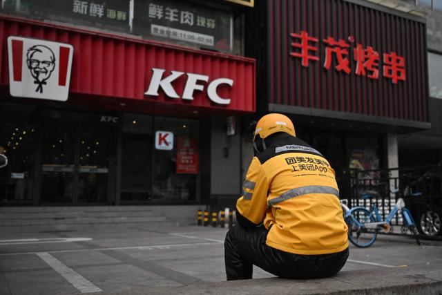 A food delivery man for Chinese company Meituan waits for orders outside a KFC branch in Beijing on November 26, 2026. (Photo by Pedro PARDO / AFP)