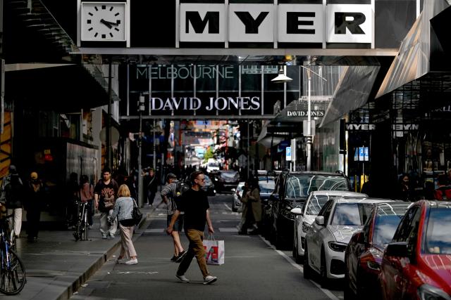 People carry their shopping bags past major retailers Myer and David Jones in Melbourne's central business district (CBD) on November 26, 2025. (Photo by William WEST / AFP)