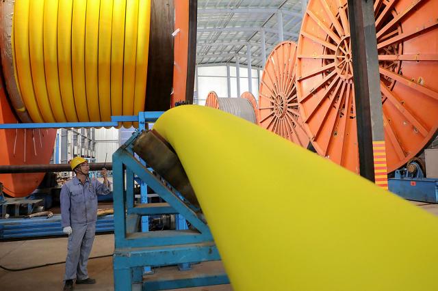 A worker inspects marine flexible pipes at a manufacturing facility in Binzhou, in China’s eastern Shandong province on November 26, 2025. (Photo by AFP) / China OUT