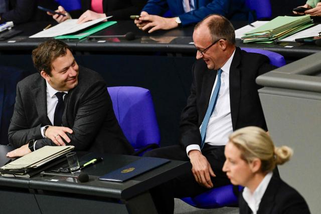 German Chancellor Friedrich Merz (C) reacts while speaking to German Finance Minister and Vice Chancellor Lars Klingbeil (L) while co-leader of the far-right Alternative for Germany (AfD) party Alice Weidel (R) addresses a sitting of the Bundestag, Germany's lower house of parliament in Berlin on November 26, 2025, during a debate on the 2026 budget. (Photo by Tobias SCHWARZ / AFP)