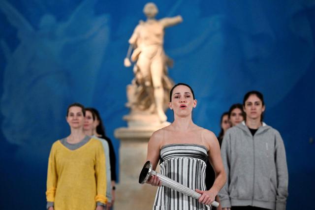Greek actress Mary Mina on the role of High Priestess takes part in the flame lighting ceremony during a rehearsal of the lighting of the Olympic flame, for the Olympic Winter Games Milano Cortina 2026, at the Museum of ancient Olympia, in Olympia, on November 25, 2025. (Photo by Aris MESSINIS / AFP)