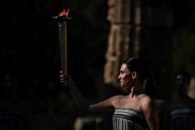 Greek actress Mary Mina on the role of High Priestess holds a torch with the Olympic Flame as part of an emergency rehearsal of the lighting of the Olympic flame for the Milano-Cortina 2026 Winter Olympic Games ceremony, in the ancient stadium of Olympia at the archaeological site, birthplace of the ancient Olympics in southern Greece, on November 24, 2025. (Photo by Aris MESSINIS / AFP)