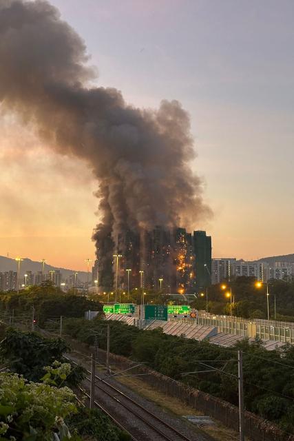 Thick smoke and flames rise as a major fire engulfs several apartment blocks at the Wang Fuk Court residential estate in Hong Kong's Tai Po district on November 26, 2025. Four people died after multiple blocks in a Hong Kong residential estate went up in flames on November 26, with local media earlier reporting that some residents were trapped. (Photo by AFP)