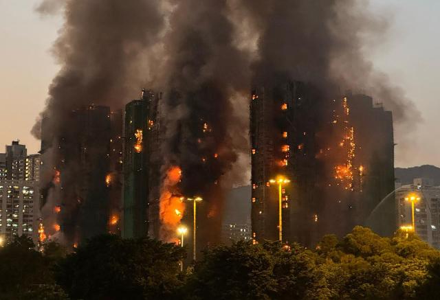Thick smoke and flames rise as a major fire engulfs several apartment blocks at the Wang Fuk Court residential estate in Hong Kong's Tai Po district on November 26, 2025. Four people died after multiple blocks in a Hong Kong residential estate went up in flames on November 26, with local media earlier reporting that some residents were trapped. (Photo by Yan ZHAO / AFP)