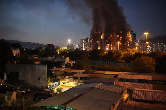 Thick smoke and flames rise as a major fire engulfs several apartment blocks at the Wang Fuk Court residential estate in Hong Kong's Tai Po district on November 26, 2025. At least four people were killed when a fire engulfed several high-rise blocks in a Hong Kong residential estate on November 26, the government said, with media reporting that some residents were trapped inside. (Photo by Yan ZHAO / AFP)