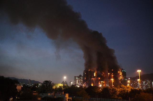Thick smoke and flames rise as a major fire engulfs several apartment blocks at the Wang Fuk Court residential estate in Hong Kong's Tai Po district on November 26, 2025. At least four people were killed when a fire engulfed several high-rise blocks in a Hong Kong residential estate on November 26, the government said, with media reporting that some residents were trapped inside. (Photo by Yan ZHAO / AFP)