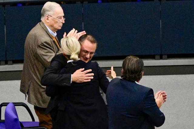 Co-leader of the far-right Alternative for Germany (AfD) party Tino Chrupalla (centre,R) is embraced by co-leader of the far-right Alternative for Germany (AfD) party Alice Weidel (centre,L) flanked by honorary chairman of the far-right Alternative for Germany (AfD) party Alexander Gauland (L) and vice-chairman of the far-right Alternative for Germany (AfD) party Stephan Brandner (R)after speaking during a general debate on the budget of the Federal Chancellery at the Bundestag, Germany's lower house of parliament in Berlin on November 26, 2025. (Photo by Tobias SCHWARZ / AFP)