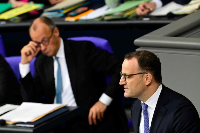 German Chancellor Friedrich Merz (L) gestures as parliamentary group leader of Germany's Christian Democratic Union (CDU) Jens Spahn (R)  speaks during a general debate on the budget of the Federal Chancellery at the Bundestag, Germany's lower house of parliament in Berlin on November 26, 2025. (Photo by Tobias SCHWARZ / AFP)