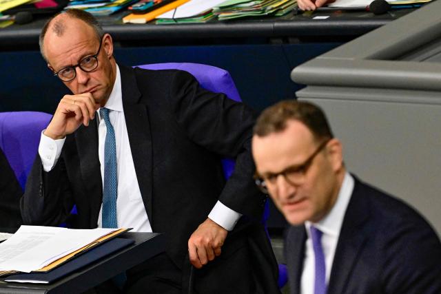 German Chancellor Friedrich Merz (L) looks over at Parliamentary group leader of Germany's Christian Democratic Union (CDU) Jens Spahn speak during a general debate on the budget of the Federal Chancellery at the Bundestag, Germany's lower house of parliament in Berlin on November 26, 2025. (Photo by Tobias SCHWARZ / AFP)