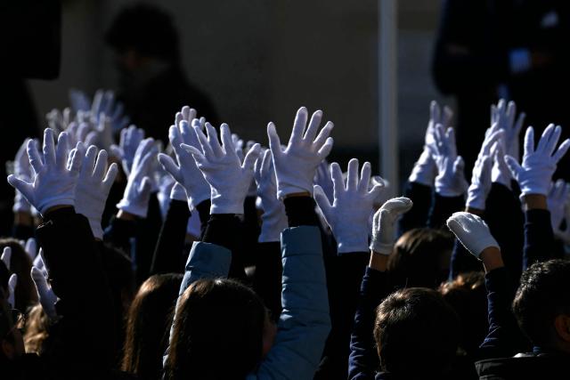 A group of children wearing white gloves wave to Leo XIV during a weekly general audience in St Peter's square in The Vatican on November 26, 2025. (Photo by Filippo MONTEFORTE / AFP)