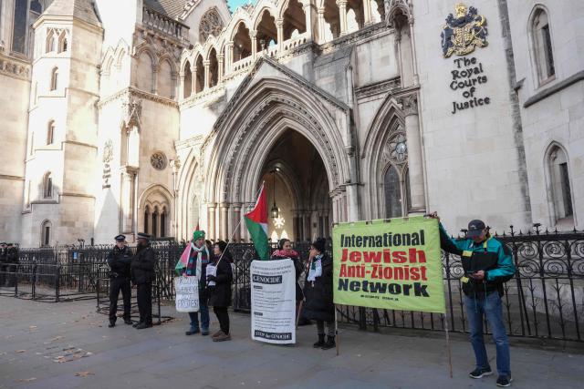 Protesters hold placards and flags during a demonstration in support of "Defend Our Juries" and their campaign against the ban on Palestine Action, outside the Royal Courts of Justice, Britain's High Court, in central London on November 26, 2025. (Photo by CARLOS JASSO / AFP)
