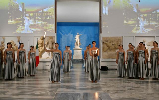 Actresses take part in the flame lighting ceremony of the Olympic flame, for the Olympic Winter Games Milano Cortina 2026, at the Museum of ancient Olympia, in Olympia on November 26, 2025. (Photo by Aris MESSINIS / AFP)