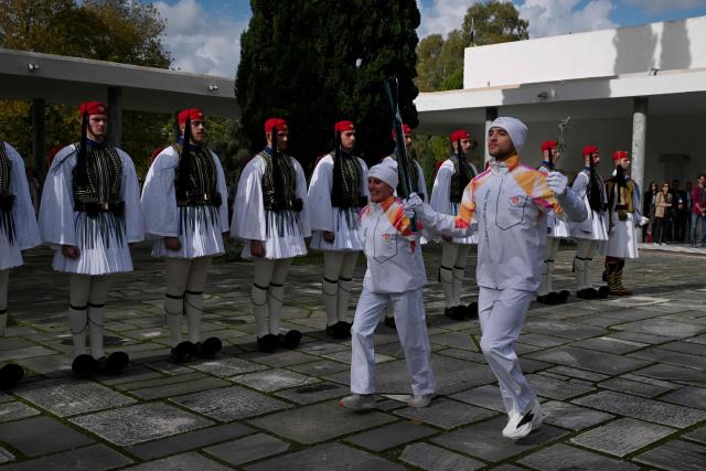 Performers take part in the flame lighting ceremony of the Olympic flame, for the Olympic Winter Games Milano Cortina 2026, at the Museum of ancient Olympia, in Olympia on November 26, 2025. (Photo by Aggelos NAKKAS / AFP)