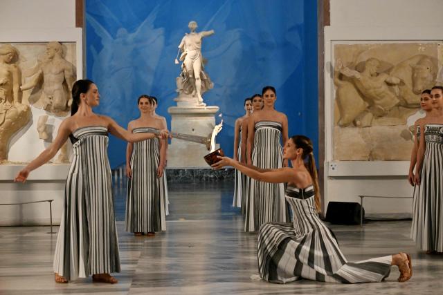 Greek actress Mary Mina (L), playing the role of the High Priestess, takes part in the flame lighting ceremony of the Olympic flame, for the Olympic Winter Games Milano Cortina 2026, at the Museum of ancient Olympia, in Olympia on November 26, 2025. (Photo by Aris MESSINIS / AFP)