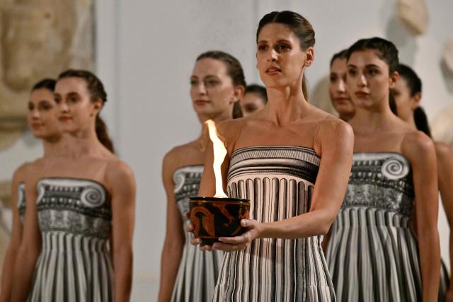 Actresses take part in the flame lighting ceremony of the Olympic flame, for the Olympic Winter Games Milano Cortina 2026, at the Museum of ancient Olympia, in Olympia on November 26, 2025. (Photo by Aris MESSINIS / AFP)