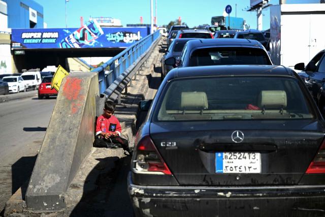 EDITORS NOTE: Graphic content / A boy counts his alms money while sitting along a roadside in Beirut on November 26, 2025. (Photo by Joseph EID / AFP)