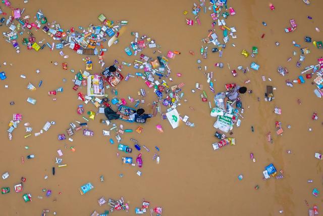 TOPSHOT - This aerial photo taken on November 26, 2025 shows people surrounded by floating products from a supermarket as they wade through flood waters in Hat Yai in Thailand's southern Songkhla province, as severe flooding affected thousands of people in the country's south following days of heavy rain. Tens of thousands of people in Thailand and neighbouring Malaysia were displaced by widespread flooding, with streets submerged, homes inundated and at least 34 dead, officials said November 26. (Photo by Arnun Chonmahatrakool / THAI NEWS PIX / AFP)
