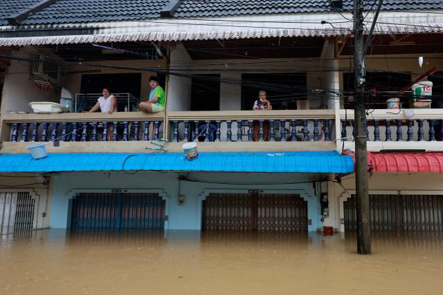 Residents look out from their homes surrounded by high flood waters in Hat Yai in Thailand's southern Songkhla province on November 26, 2025, as severe flooding affected thousands of people in the country's south following days of heavy rain. Tens of thousands of people in Thailand and neighbouring Malaysia were displaced by widespread flooding, with streets submerged, homes inundated and at least 34 dead, officials said November 26. (Photo by Sarot Meksophawannakul / THAI NEWS PIX / AFP)