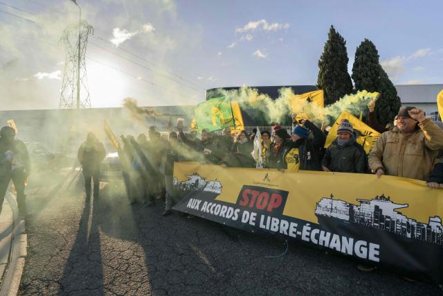 Members of French farmer union Confederation Paysanne demonstrate behind a banner reading in French "Stop free trade agreements" during an action outside a logistics centre of French-Moroccan importer of Tomatoes from Western Sahara Azura to protest "the unfair competition faced by producers in the European Union and the violation of the rights of the Sahrawi people", in Perpignan, southern France, on November 26, 2025.

Environmental activists of the French farmers union « Confederation Paysanne » are holding a banner and smoke bombs during an action to search for tomatoes illegally labeled as coming from Morocco instead of Western Sahara by logistics center Azura, a fruit and vegetable importer in Perpignan, Southwestern France, November 26, 2025. (Photo by Idriss Bigou-Gilles / AFP)