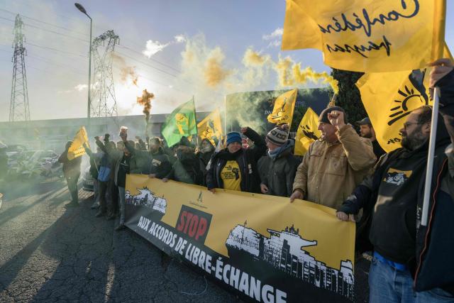Members of French farmer union Confederation Paysanne demonstrate behind a banner reading in French "Stop free trade agreements" during an action outside a logistics centre of French-Moroccan importer of Tomatoes from Western Sahara Azura to protest "the unfair competition faced by producers in the European Union and the violation of the rights of the Sahrawi people", in Perpignan, southern France, on November 26, 2025.

Environmental activists of the French farmers union « Confederation Paysanne » are holding a banner and smoke bombs during an action to search for tomatoes illegally labeled as coming from Morocco instead of Western Sahara by logistics center Azura, a fruit and vegetable importer in Perpignan, Southwestern France, November 26, 2025. (Photo by Idriss Bigou-Gilles / AFP)