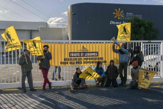 Members of French farmer union Confederation Paysanne block an entrance of a logistics centre of French-Moroccan importer of Tomatoes from Western Sahara Azura during a action to protest "the unfair competition faced by producers in the European Union and the violation of the rights of the Sahrawi people", in Perpignan, southern France, on November 26, 2025. (Photo by Idriss Bigou-Gilles / AFP)