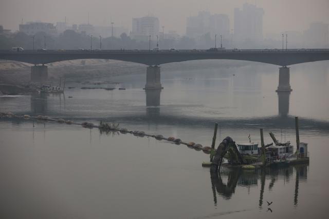 Vehicles cross the Republic Bridge over the Tigris River in central Baghdad as thick smog envelops the city on November 26, 2025. (Photo by AHMAD AL-RUBAYE / AFP)