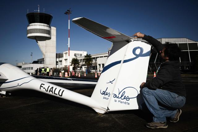 Engineer Jean-Baptiste Loiselet inspects his Sol.Ex solar glider, the world's first solar glider that combines wind and solar energy to fly autonomously without emitting CO2, at the General Aviation Days event at Pau-Pyrénées airport, south-western France, on November 26, 2025. The fifth edition of the professional gathering brings together pioneers of decarbonized light aviation to discuss new energy solutions including electricity, hydrogen and sustainable aviation fuels. (Photo by Philippe LOPEZ / AFP)